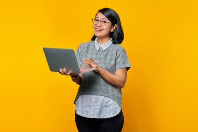 Woman smiling at you while holding a laptop